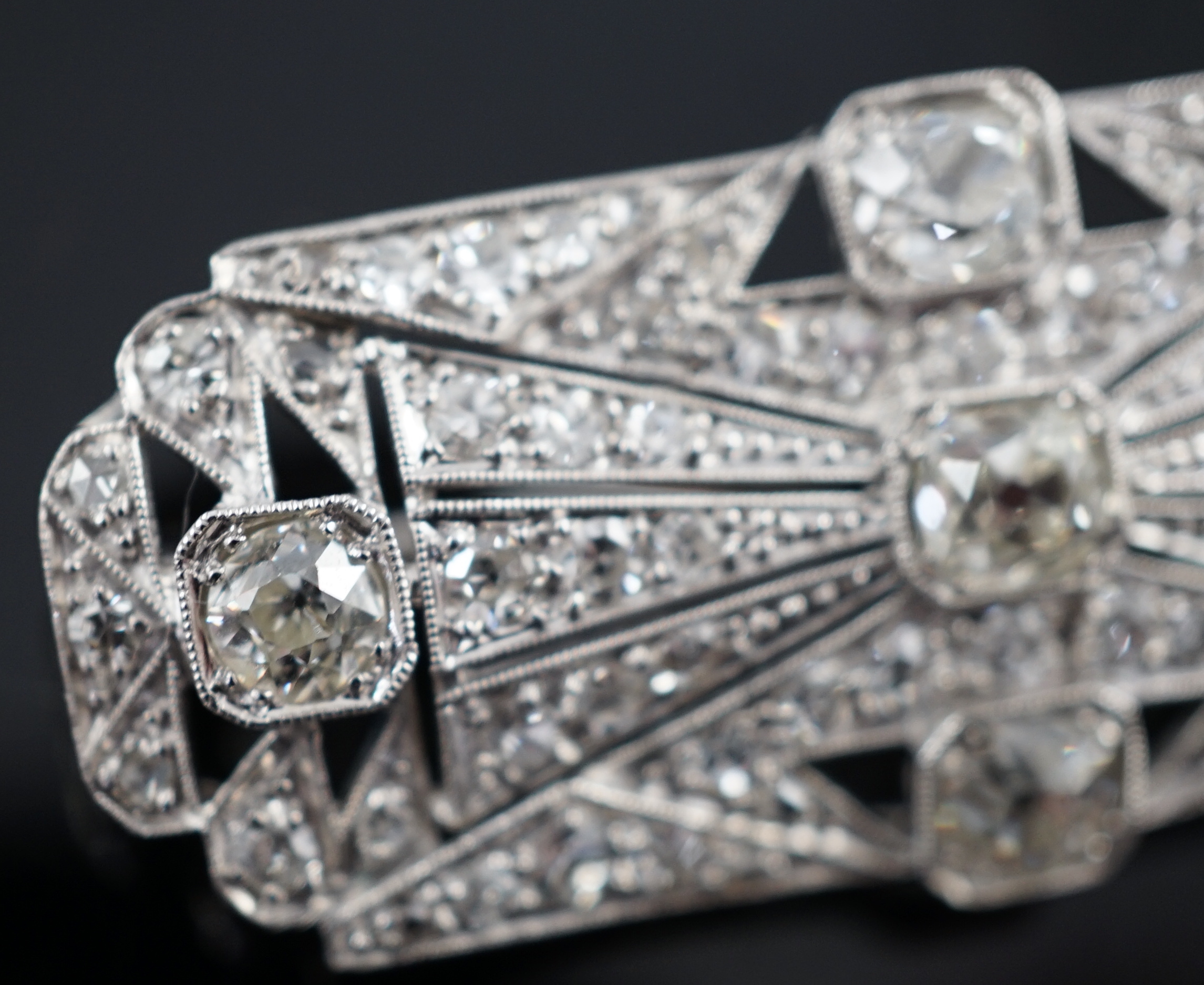 An Art Deco pierced platinum and millegrain set diamond cluster shaped rectangular brooch